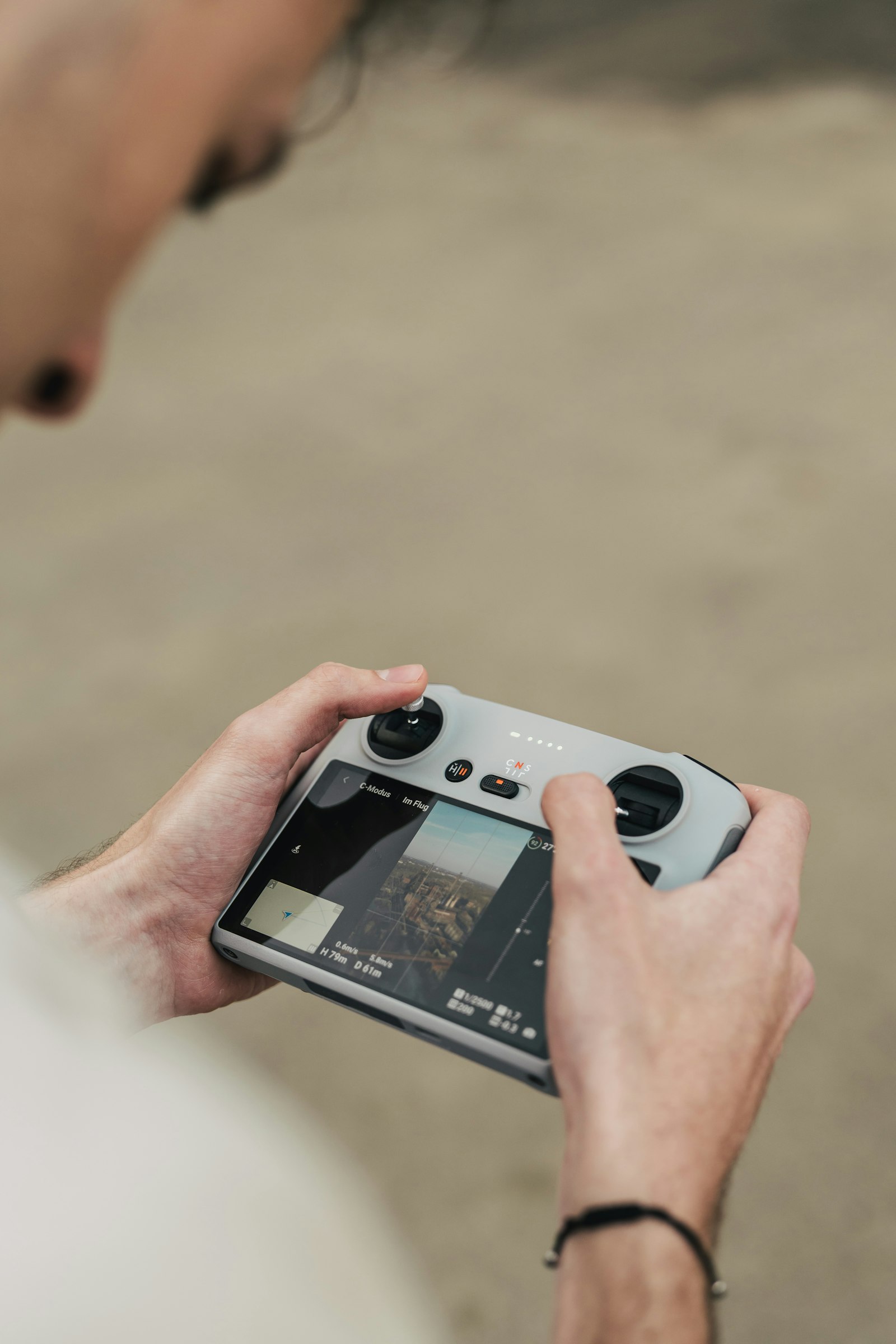 Drone pilot handling a remote controller with live video feed